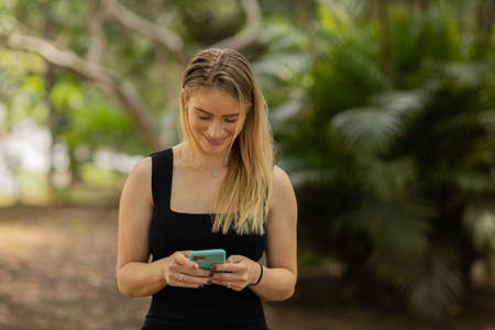 Young woman using a smartphone at night time with city view landscape in the background. High quality photo. photo. Mobile phone, technology, urban concept.の写真素材
