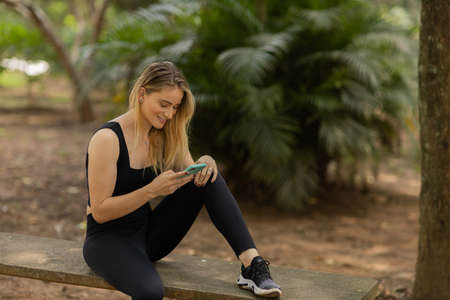 Young woman using a smartphone at night time with city view landscape in the background. High quality photo. photo. Mobile phone, technology, urban concept.の写真素材
