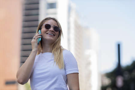 Young woman using a smartphone at night time with city view landscape in the background. High quality photo. photo. Mobile phone, technology, urban concept.の写真素材