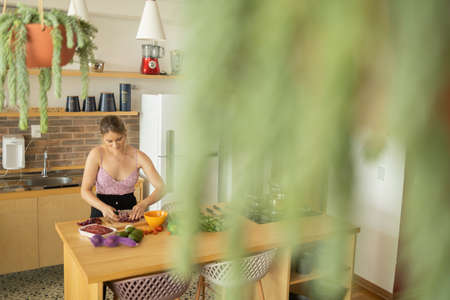 Happy and healthy young woman meal prepping whole vegetarian meal in the kitchen. High quality photo. Feel good, healthy and health concept.の写真素材