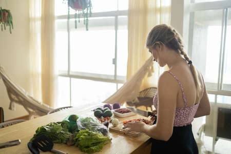 Happy and healthy young woman meal prepping whole vegetarian meal in the kitchen. High quality photo. Feel good, healthy and health concept.の写真素材