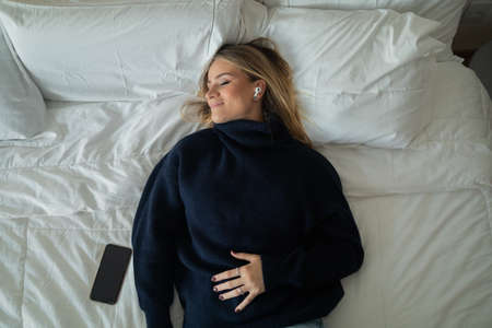 Young woman using a smartphone at night time with city view landscape in the background. High quality photo. photo. Mobile phone, technology, urban concept.の写真素材