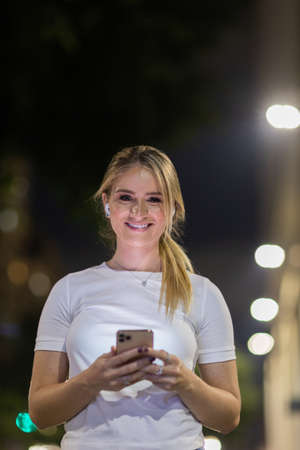 Young woman using a smartphone at day time with a green park in the background. High quality photo. Mobile phone, technology, urban concept. high quality photoの写真素材