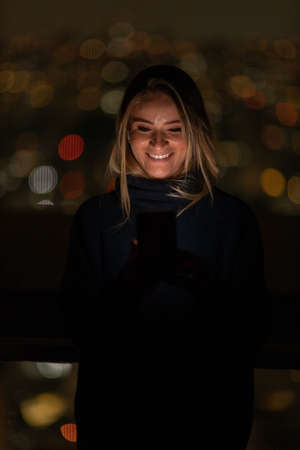Young woman using a smartphone at day time with a green park in the background. High quality photo. Mobile phone, technology, urban concept. high quality photoの写真素材