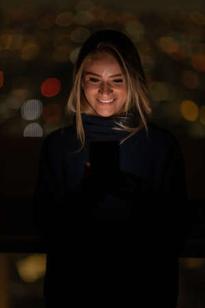 Young woman using a smartphone at day time with a green park in the background. High quality photo. Mobile phone, technology, urban concept. high quality photoの写真素材