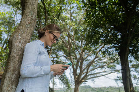 Young woman using a laptop at day time with a green park in the background. High quality photo....