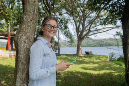 Young woman using a smartphone at day time with a green park in the background. High quality photo. Mobile phone, technology, urban concept. high quality photoの写真素材
