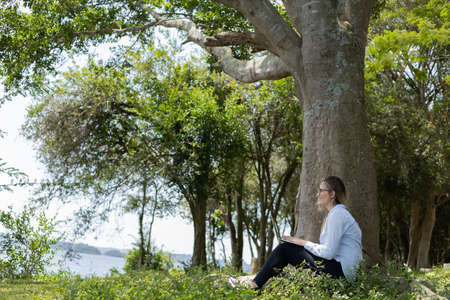 Young woman using a smartphone at day time with a green park in the background. High quality photo. Mobile phone, technology, urban concept. high quality photoの写真素材