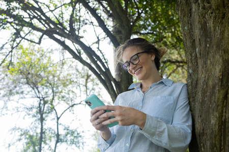 Portrait of smiling young woman at a park on a beautiful sunny day. Woman with open arms in front of...