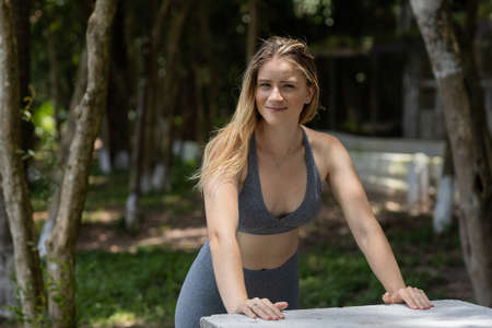 Young woman using a laptop at day time with a green park in the background. High quality photo. Mobile phone, technology, urban concept.の写真素材