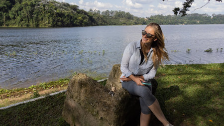 Young woman with sunglasses using a smartphone at day time at a green park with a lake - body of water. in the background High quality photo. Mobile phone, technology, urban concept. high quality photoの写真素材