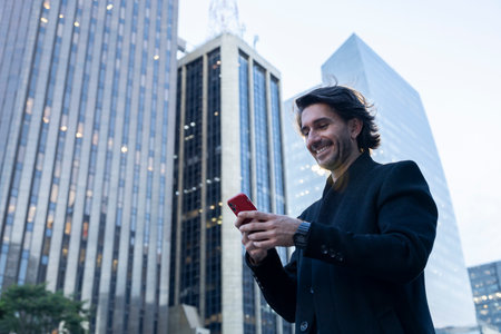 View of young man with smartphone at twilight with city view landscape in the background.の写真素材