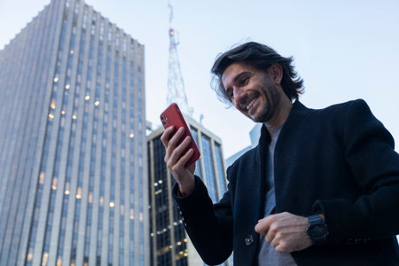 View of young man with smartphone at twilight with city view landscape in the background. High quality photo.の写真素材