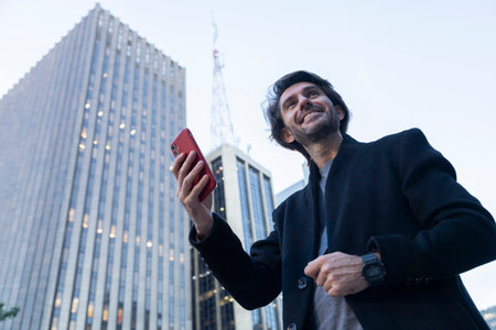 View of young man with smartphone at twilight with city view landscape in the background. High quality photo.の写真素材