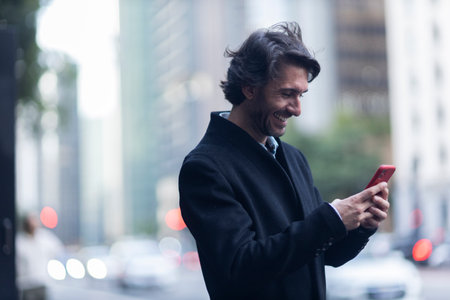 View of young man with smartphone at daytime with city view landscape in the background. High quality photo.の写真素材