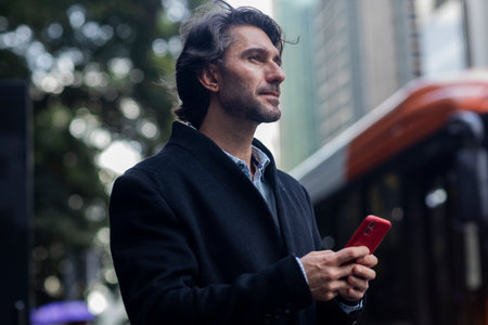 View of young man with smartphone at daytime with city view landscape in the background. High...