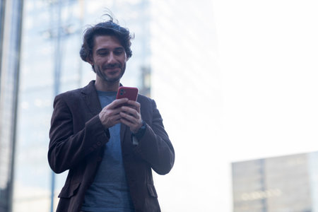 View of young man with smartphone at daytime with city view landscape in the background. High...