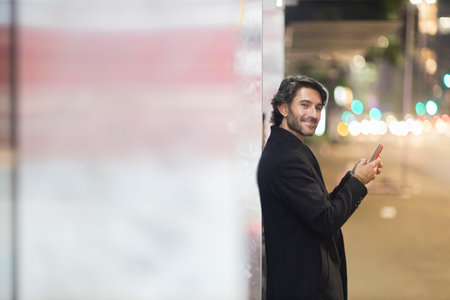 View of young man using a smartphone at night time with city view landscape in the background. High quality photo. View of young man using a smartphone at night time with city view landscape in the background. High quality photo.の写真素材