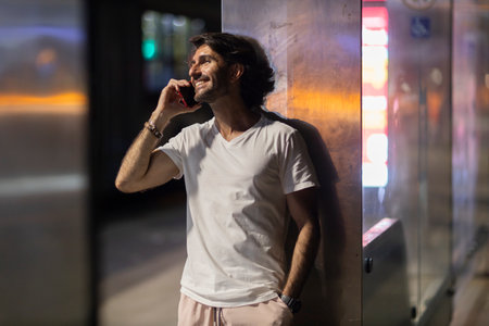 View of young man using a smartphone at night time with city view landscape in the background. High quality photo.の写真素材