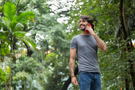 View of a young man with smartphone at daytime in a green park in the city. High quality video.の写真素材
