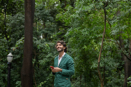 View of a young man with smartphone at daytime in a green park in the city. High quality video.