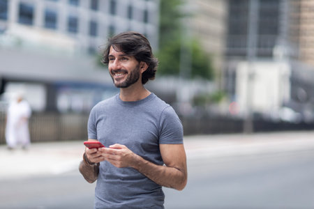 View of a young man with smartphone at daytime with city view landscape in the background. High quality photo.の写真素材