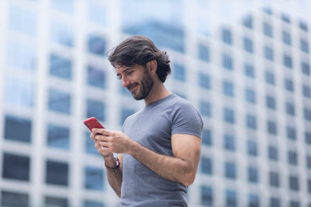 View of a young man with smartphone at daytime with city view landscape in the background. High quality photo.の写真素材