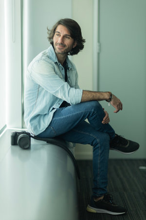 Portrait of a young Latin American Caucasian man holding a camera. Photographer, Videographer, professionalの写真素材