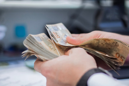Human hand of businessman working in exchange office/bank. He is counting money and giving cash money to a customer.の写真素材