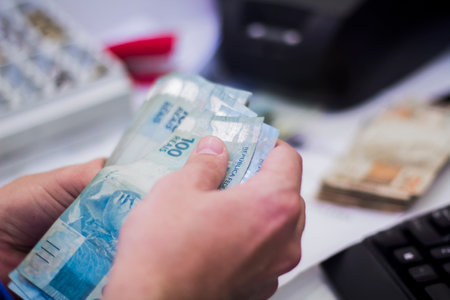 Human hand of businessman working in exchange office/bank. He is counting money and giving cash money to a customer. Reais 100 reais bills.の写真素材