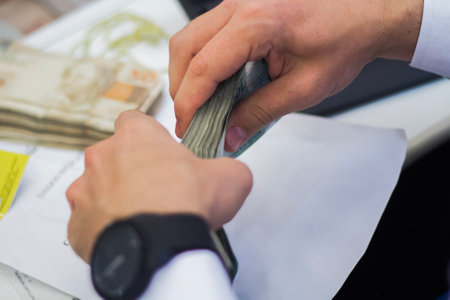 Human hand of businessman working in exchange office/bank. He is counting money and giving cash money to a customer. Brazilian Reais 50 reais bills.の写真素材