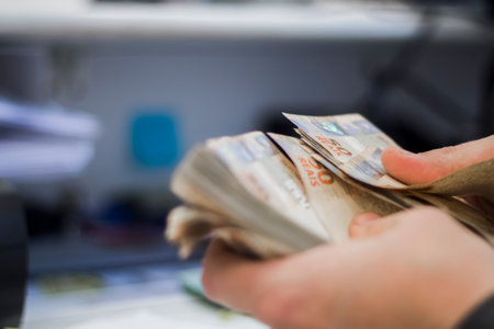 Human hand of businessman working in exchange office / bank. He is counting money and giving cash money to a customer. Brazilian Reais 50 reais bills.の写真素材