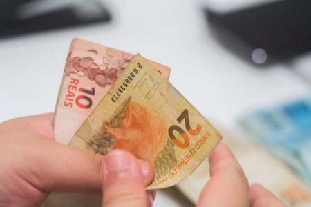Human hand of businessman working in exchange office / bank. He is counting money and giving cash money to a customer. Brazilian Reais.の写真素材