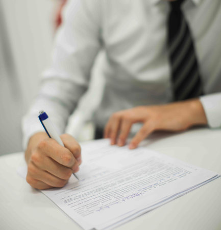 Crop shot of a business person with pen signing document / contract at desk in daylight.の写真素材