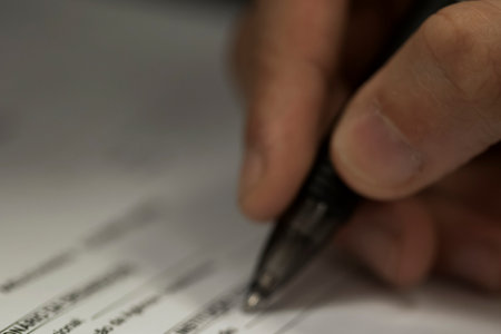 Crop shot of a business person with pen signing document / contract at desk in daylight.の写真素材