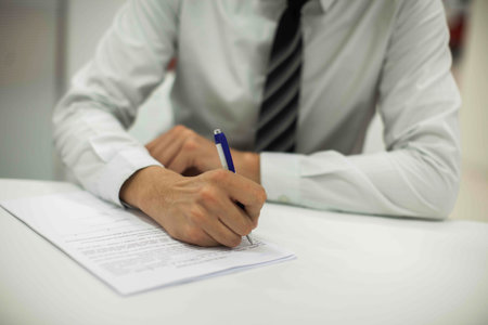 Crop shot of a business person with pen signing document / contract at desk in daylight.の写真素材