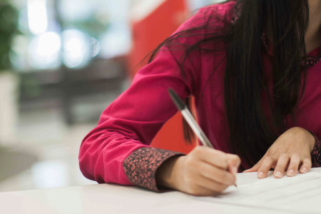 Crop shot of a business person with pen signing document / contract at desk in daylight.の写真素材