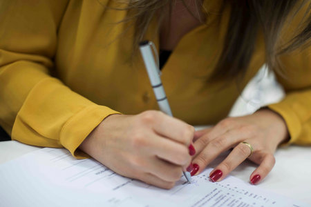 Crop shot of a business person with pen signing document / contract at desk in daylight.の写真素材