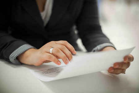 Crop shot of a business person with pen signing document / contract at desk in daylight.の写真素材