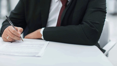 Crop shot of a business person with pen signing document / contract at desk in daylight.の写真素材