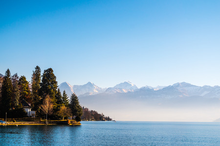 Lake Thun and typical Switzerland village near town of Interlaken with a view of Alps mountain at backgroundの写真素材