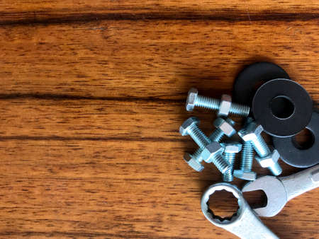 Screws, bolts, and hand tools placed together on a brown wood floor