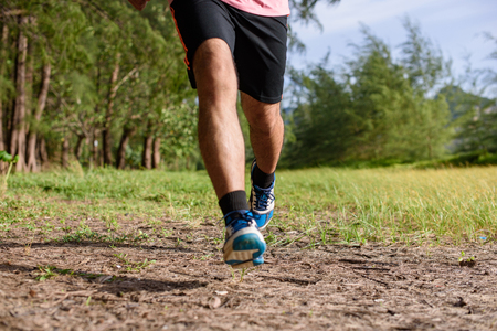 Asian Man running on forest path during sunset, close up legs and feetの写真素材