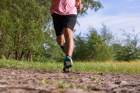 Asian Man running on forest path during sunset, close up legs and feetの写真素材