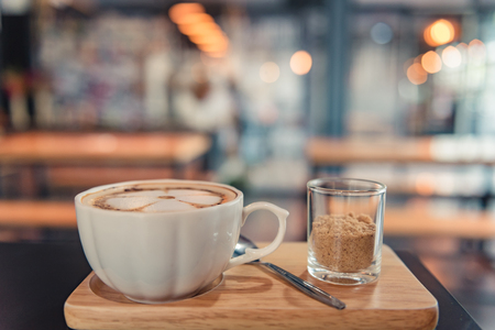 Hot Coffee cup and brown sugar on the wooden tray in coffee shop backgroundの写真素材
