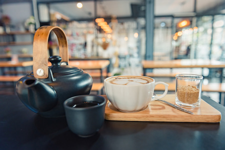 Latte art coffee, cup of hot coffee on wooden tray and dark tableの写真素材
