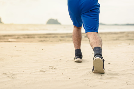 Man runner legs running close up on shoe, Men jogging on the beachの写真素材