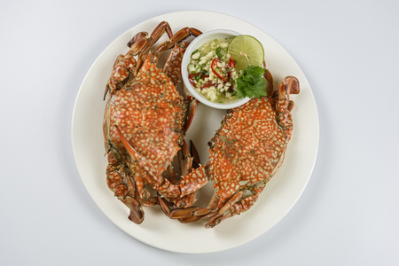 Steamed blue crab on white plate with spicy seafood sauceの写真素材