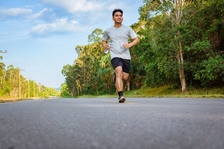 Young male jogger athlete training and doing workout outdoors on street  road