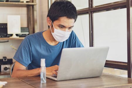 The man wear a mask to protect against the Coronavirus Covid-19, work from homeの写真素材